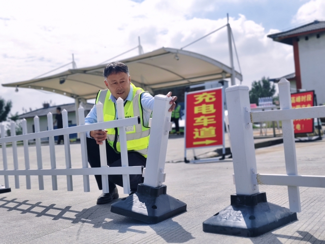 為提升節假日期間通行效率，濉溪服務區在節前提前完成油電車道分離工作。圖為濉溪服務區物業安全職員王仲連在擺放隔離柵欄。.jpg